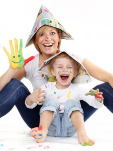 Cute boy and mother have coloured hands, playing together